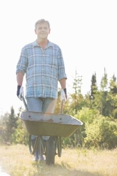 Portrait of male gardener pushing wheelbarrow at garden