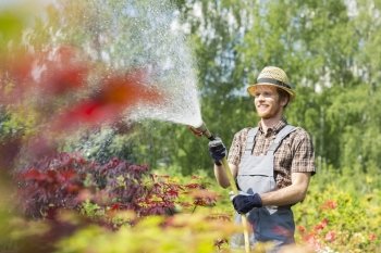Smiling man watering plants at garden