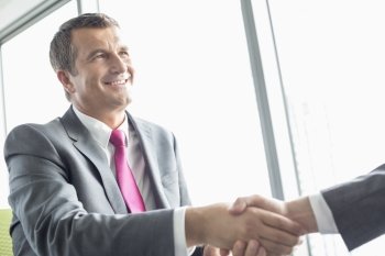 Smiling mature businessman shaking hands with partner in office