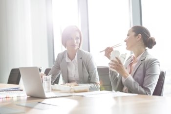 Young businesswomen having lunch at table in office