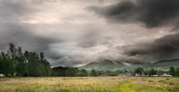 Beautiful landscape across countryside to mountains in distance with moody sky