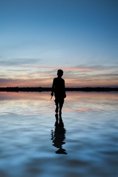 Conceptual image of young boy walking on water in sunset landscape