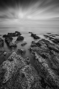 Black and white landscape looking out to sea with rocky coastline and beautful sunset sky