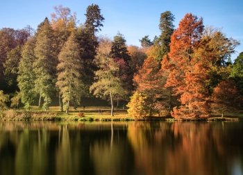Beautiful Autumn lake landscape with vibrant colors reflected in still waters