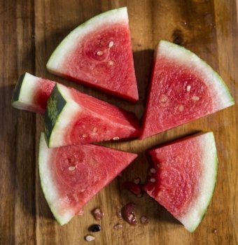 Sliced juicy watermelon on wooden chopping board in kitchen