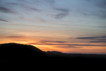 Vibrant sunset landscape over countryside hills silhouette