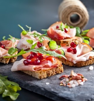 Sliced prosciutto with herbs and pomegranate seeds