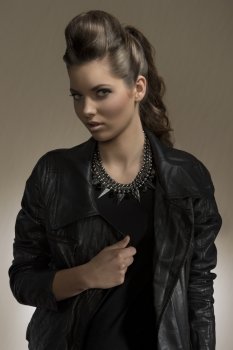 portrait of cute brunette girl with long wavy hair and fashion casual style. wearing leather jacket and rock necklace  