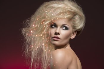 close-up shoot of blonde young lady with bushy creative hair-style, cute make-up, naked shoulders on red background