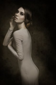 fashion elegant girl posing with romantic expression, elegant hair-style and gray dress. Slim perfect body