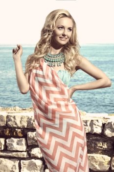 happy woman in summertime smiling and wearing pareo on bikini, turquoise big necklace and long wavy blonde hair