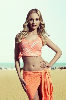 sexy blonde girl with summer style posing with orange pareo, singlet and wavy long hair. Perfect body