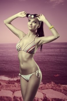 sexy brunette girl posing with colorful bikini in vacation, wearing  sunglasses on the head, fashion wrist watch and ponytail hair-style