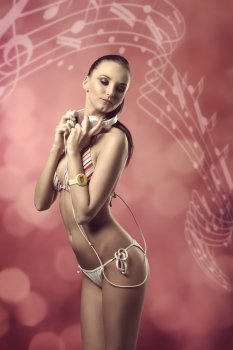 sexy woman with bikini listening music with headphones, in sensual pose
