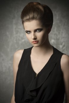 fashion portrait of very pretty young girl with creative elegant hair-style, cute make-up and stylish black dress