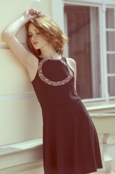 pretty young girl with natural hair-style and stylish black dress posing in outdoor fashion shoot near building 