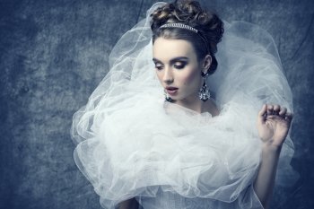 charming lady wearing like sophisticated dame with baroque romantic dress, elegant hair-style, shiny tiara, precious earrings and stylish make-up.