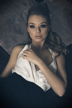 fashion portrait of elegant pretty lady , she has noce hair style , and she is looking in camera with her stunning eyes , laying on pillow