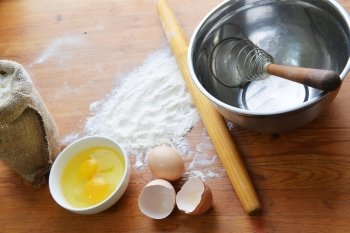 Kitchen rolling pin, eggs  and flour on wooden background