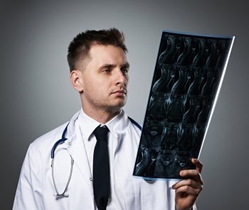 Medical doctor with MRI spinal scan portrait against grey background 