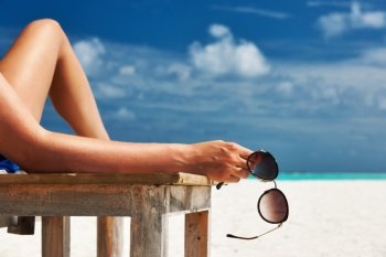 Woman at beautiful beach holding sunglasses