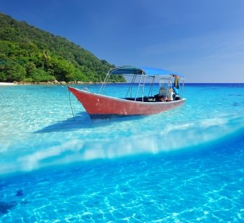 Beautiful beach and motor boat with white sand bottom underwater and above water split view