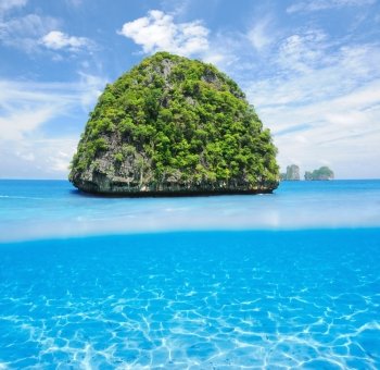 Beautiful uninhabited island in Thailand with white sand bottom underwater and above water split view