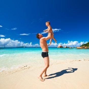 Two year old baby boy and his father playing on beach at Seychelles