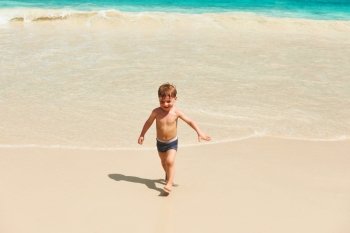 Two year old baby boy playing on beach at Seychelles