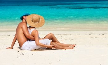 Couple in white relax on a tropical beach at Maldives