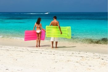 Couple with inflatable rafts on a tropical beach at Maldives
