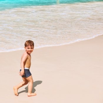 Two year old baby boy playing on beach at Seychelles