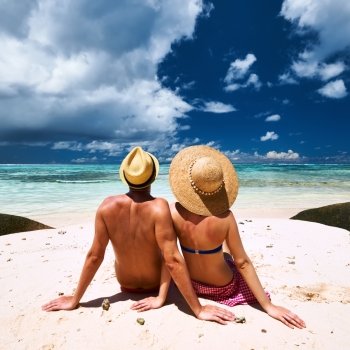Couple relaxing on a tropical beach Anse Source d’Argent at Seychelles, La Digue.