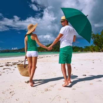 Couple in green with umbrella on a tropical beach at Seychelles