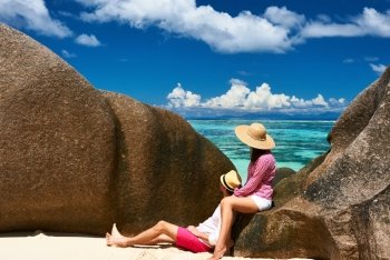 Couple relaxing among granite rocks on a tropical beach Anse Source d’Argent at Seychelles, La Digue.