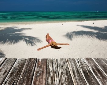 Woman in bikini at tropical beach under the palm tree shadow