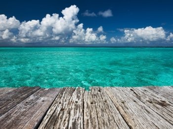 Crystal clear turquoise water and old wooden pier at tropical maldivian beach