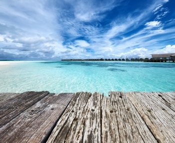 Beautiful beach and old wooden pier with water bungalows at Maldives