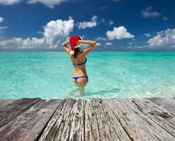 Woman in santa’s hat in bikini at tropical beach