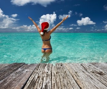 Woman in santa’s hat in bikini at tropical beach