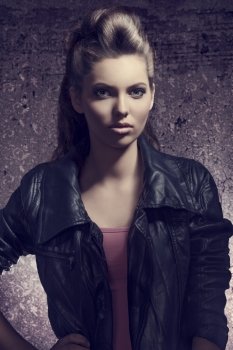 fashion portrait with dark atmosphere of pretty young girl with brown modern hair-style and casual leather jacket   