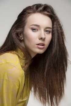 portrait of sensual female with long brown hair and  sexy yellow transparent nightgown looking in camera   
