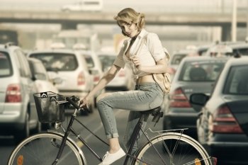 portrait of eco-friendly woman on a bicycle  with casual style and small backpack in sensual pose looking in camera  

