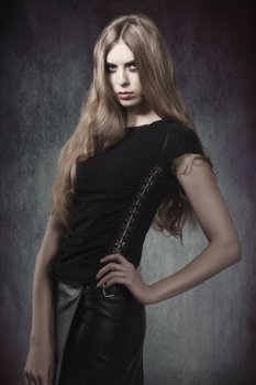 fashion portrait of gothic girl with Halloween make-up and dark dress in sensual pose with long blonde hair 