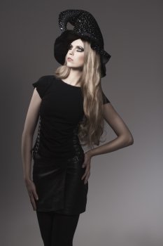 portrait of fashion Halloween woman with gothic style, leather skirt, witch hat and creative make-up