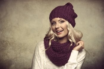 grunge portrait of young and sexy blond girl wearing purple scarf and hat in winter dress over white