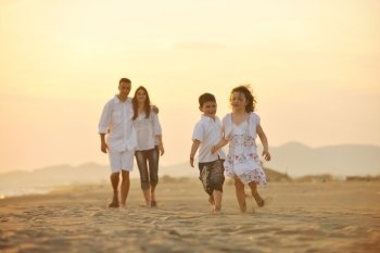 happy young family have fun on beach run and jump  at sunset