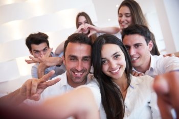 group of friends taking selfie photo with tablet at modern home indoors