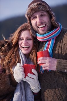 portrait of happy young couple outdoor on winter day drinking warm tea
