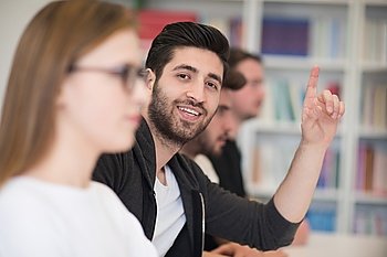 group of  smart students raise hands up in school  classroom on class